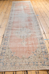 Distressed vintage Sparta runner with faded blush field and denim blue border motifs.