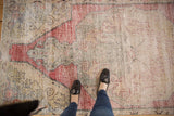 Distressed Oushak runner texture with faded cherry red, saffron, and silver arabesque patterns.