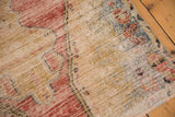 Distressed Oushak rug texture revealing faded cherry red, saffron, and silver floral motifs.