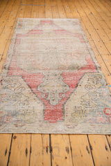Faded cherry red and saffron yellow tones on the worn end of the vintage Oushak runner.
