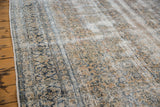 Distressed vintage Kashan rug texture, showing muted ivory and teal floral vinery.