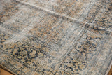 Distressed vintage Kashan rug detail showing worn pile, faded floral design, ivory, gold, teal.