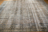 Distressed Kashan carpet in faded ivory, sand, pale gold, and dark teal allover floral design.