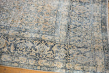 Distressed vintage Kashan carpet detail, showcasing worn ivory and dark teal floral motifs.