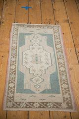 Distressed Oushak rug corner revealing faint foundation, dusty blue, beige patterns, blush selvage.