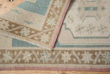 Hand-knotted vintage Oushak rug's folded corner revealing blush selvage and distressed blue patterns.