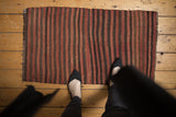 Striped Turkish Kilim rug showing varied brick red, wine red, and brown bands.