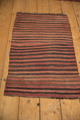 Edge of a vintage Turkish Kilim rug, highlighting brick red, coffee brown, and charcoal stripes.
