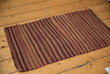 Corner detail of vintage Turkish Kilim rug, showing variegated red and brown striped weave.