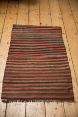 Hand woven Turkish Kilim rug's fringe with varied brick red, coffee brown, charcoal stripes.