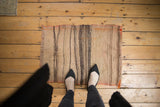 Distressed Turkish Kilim rug featuring varying striped bands and a fringed top edge.
