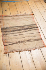 Detail of fringed end and varying ivory, charcoal, and orange striped kilim bands.
