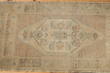 Detail of Distressed Oushak rug: even wear on ivory field, pale blue medallion, floral motifs.