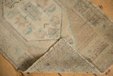 Distressed vintage Oushak rug's hand-knotted foundation and worn pile with secured selvage.