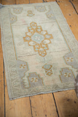 Distressed Oushak rug's muted pale bronze and silver mauve geometric medallion and border.