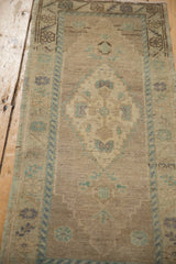 Ivory diamond medallion with serrated contour, pale green plants on distressed Oushak rug.
