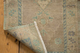 Vintage Distressed Oushak rug corner shows textured pile, pale ocean green motif, and hand-knotted foundation.