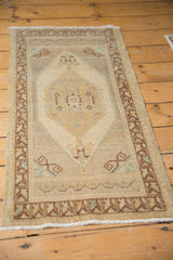 Oushak mat runner's bottom fringe and geometric border, showing even wear and rams horn motifs.
