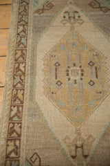 Oushak rug's geometric brown border and distressed beige-gold medallion detail with sea foam accents.