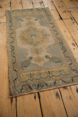 Vintage distressed Oushak rug corner, soft pile with faded ivory, gold, and green motifs.
