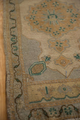 Distressed Oushak rug border and field detail with faded gold floral motifs and green vines.