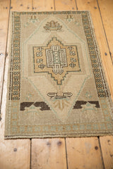 Vintage distressed Oushak rug showing secured end and geometric floral finials.