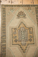 Distressed vintage Oushak rug's geometric stylized floral motif in soft beige tones.
