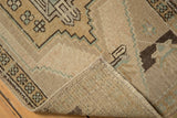Folded corner of a distressed Oushak rug, showing geometric patterns, even wear, and original selvages.