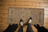 Vintage distressed Oushak runner's hexagonal mauve medallion, pale turquoise motifs.