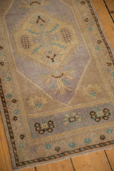 Lower corner of distressed Oushak runner, mauve, pale gold, turquoise geometric border.