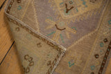 Folded corner of vintage Oushak rug, showing distressed pile, intact selvage, and reverse.