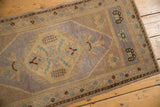 Distressed vintage Oushak runner's upper corner with pale gold, mauve, and turquoise motifs.