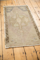 Worn pile and muted mauve, beige tones of a distressed Oushak rug corner.