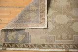 Distressed vintage Oushak rug corner, showing hand-knotted reverse and muted beige, mauve pile.