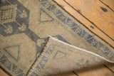 Distressed Oushak rug showing worn beige pile, woven foundation, and intact selvage.