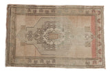 Vintage distressed Oushak rug mat with stepped medallion, pinwheel florals, and soft ivory, beige, blush tones.