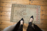 Hand-knotted distressed Oushak mat, with ivory, blush, and charcoal floral medallion.