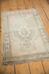 Distressed vintage Oushak rug corner, soft blush and ivory borders, revealing even knot head wear.