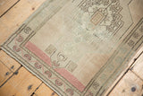 Angled close-up of vintage Turkish Oushak rug, showing blush borders and worn pile.