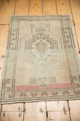 Lower portion of distressed Oushak rug showing blush, beige, and charcoal motifs with even wear.