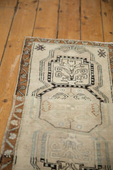 Distressed Oushak rug detail: rams horns vinery in ivory medallion and bronze vine border.