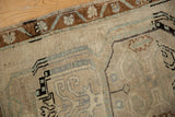Detail of a distressed Oushak rug displaying heavy abrash, bronze meandering vine border, and pale sea foam green patterns.