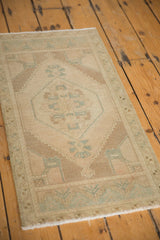 Hexagonal medallion and floral bouquet details on distressed Oushak rug in pale tones.