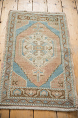 Distressed Oushak rug mat detail: pale terra cotta, ocean blue, bronze tones, side selvage.
