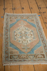 Fringed corner of distressed Oushak rug, featuring light blue and terra cotta geometric border.