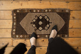 Vintage Turkish Oushak rug showing asymmetric chocolate brown medallion with ivory geometric fills.