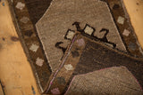 Folded vintage Oushak rug revealing gray pile, dark diamond patterns, and woven foundation.