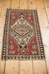 Distressed vintage Oushak mat shows hexagonal medallion, floral field, and time-softened rust tones.
