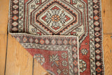 Folded vintage Oushak rug shows distressed pile, floral field, hexagonal medallion, and original selvage.