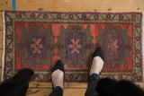 Top corner of Oushak rug, blush and aubergine floral medallion with olive green vine border.